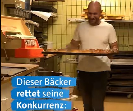 Baker carrying a tray of bread in a bakery, with a blue caption: 'Dieser Bäcker rettet seine Konkurrenz:'